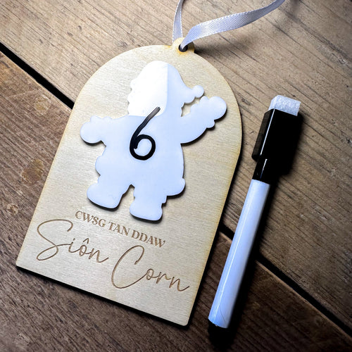 Wooden tag with a white cutout number '6' and a pen on a wooden surface